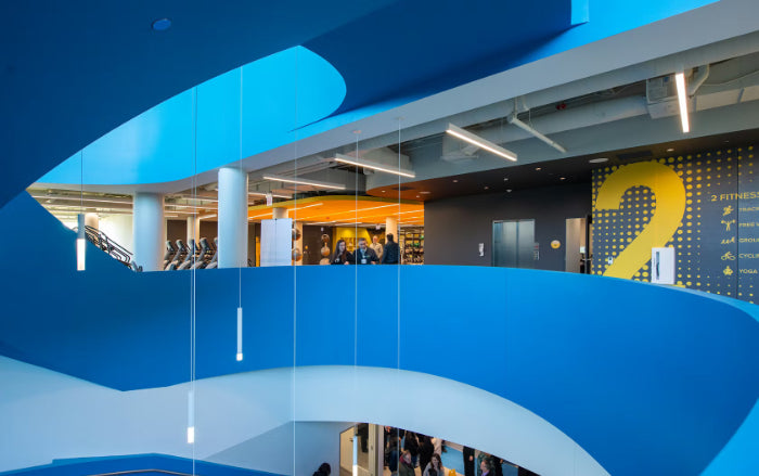 Modern indoor staircase with blue walls and glass balustrades in a building interior.